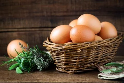 Fresh eggs in a rustic willow basket against dark wooden background Stock Photos