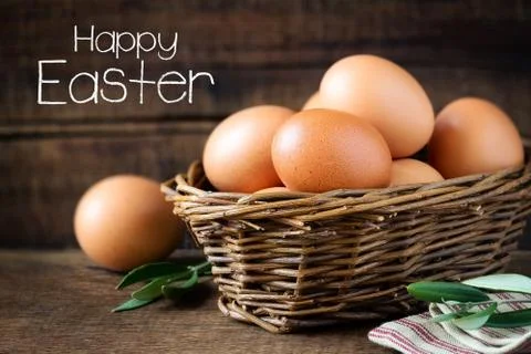 Fresh eggs in a rustic willow basket against dark wooden background Stock Photos