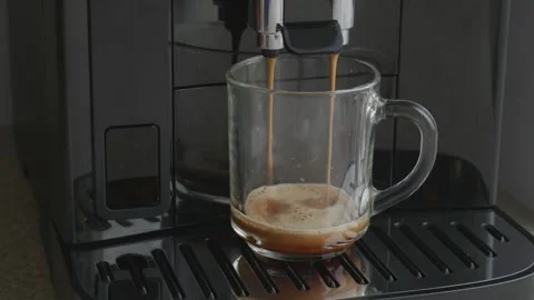 Fresh espresso dripping from coffee machine into glass cup, close up. Stock Footage 346452152