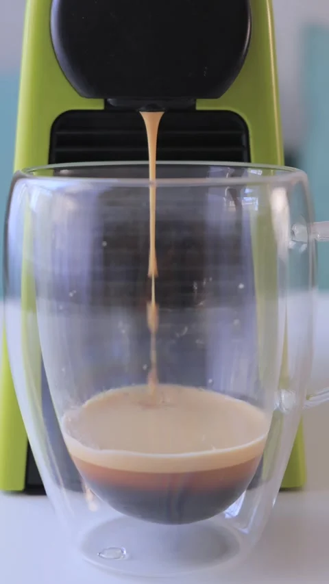 Fresh espresso pouring from coffee machine into glass cup with crema in kitchen Stock Footage 316319192
