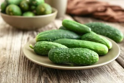 Fresh farm cucumbers in rustic plates on wooden barn board table Stock Photos