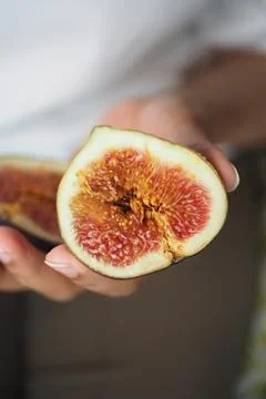 Fresh fig cut in half held in a person's hand Stock Photos