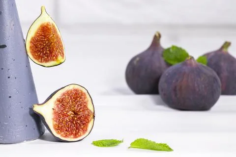 Fresh Fig with mint leaf on gray stands and podiums over white background Stock Photos