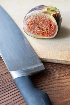 Fresh fig sliced in half with a chef knife on a rustic wooden board Stock Photos