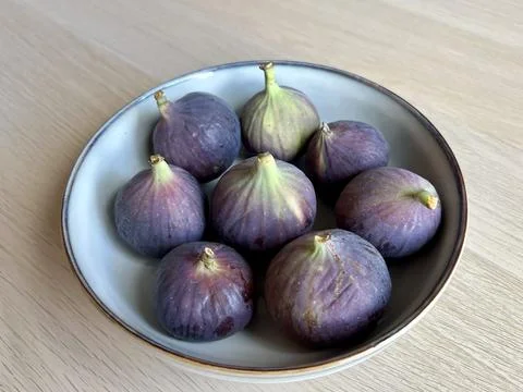 Fresh figs in a ceramic plate placed on a wooden table Stock Photos