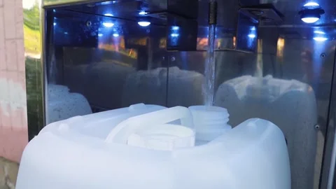 Fresh filtered water pouring into a plastic canister at a self-service vending m Stock Footage 339879149