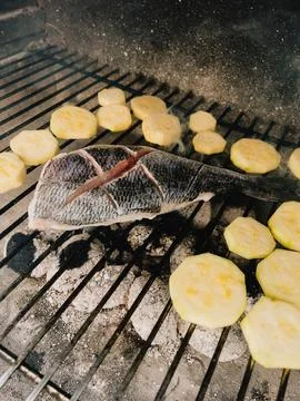Fresh fish and zucchini slices grilling over hot charcoal barbecue, filling air Foto stock
