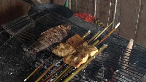 Fresh fish close up cooking on grill with fire and smoke in amazon Stock Footage 166526889