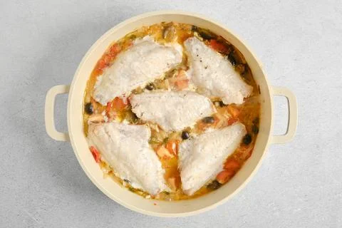 Fresh fish fillets cooked with vegetables in a large pot on a gray surface Stock Photos
