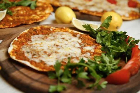 Fresh flatbread with cheese, herbs, and vegetables on wooden boards 库存照片