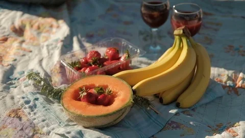 Fresh fruit and two glasses with red wine lie on the beach. Stock Footage 78511602