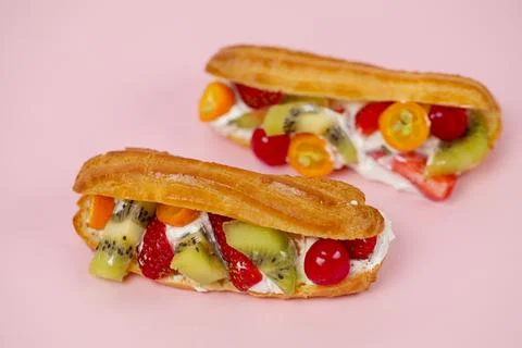 Fresh fruit eclairs on a pink background 库存照片