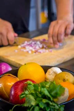 Fresh fruit in the kitchen with chef cutting onion to prepare food Фото