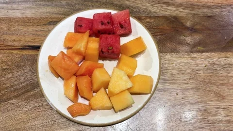 Fresh fruit platter featuring watermelon papaya and melon cubes on ceramic plate Stock Footage 337970166