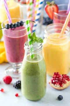 Fresh fruit smoothies with colourful straws surrounded by fresh fruit. Stock Photos