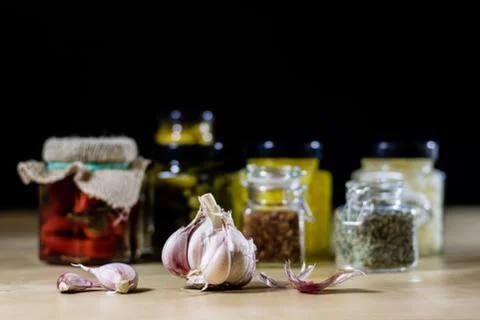 Fresh garlic smelling on the kitchen table. Mortar and kitchenware. Wooden ta Stock Photos