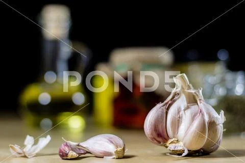 Fresh garlic smelling on the kitchen table. Mortar and kitchenware. Wooden ta Stock Photos