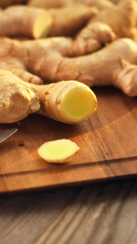 Fresh ginger rhizomes on a kitchen counters cutting board release a pungent Stock Footage 334397358