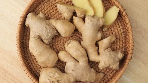 Fresh ginger root and slices rotating in a wicker basket Vidéo 346986056