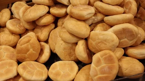 Fresh golden bread rolls arranged in a busy supermarket bakery display Stock Footage 345358852