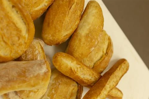 Fresh golden bread rolls piled on white surface with closeup crust texture view Stockfoto's
