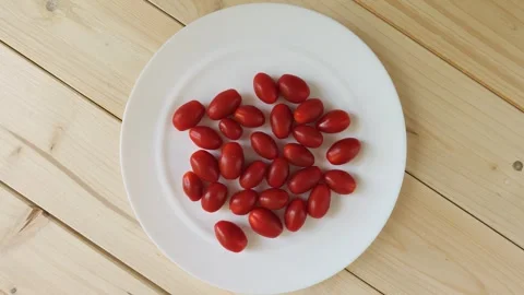 Fresh grape tomatoes spinning on a white plate Stock Footage 336464520