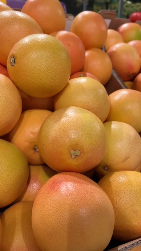 Fresh grapefruits are piled in cardboard boxes on a supermarket display. Video stock 339694569