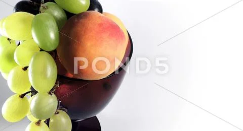 Fresh grapes and peaches in big wineglass Stock Photos