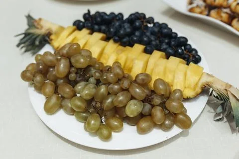 Fresh grapes and pineapple slice arranged on a white plate Foto stock