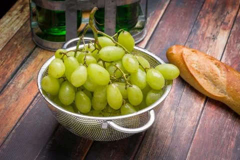 Fresh grapes in stainless steel colander on a wood surface. Stock Photos