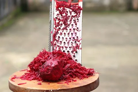 Fresh grated beetroot using stainless steel vegetable grater held in hand Foto stock