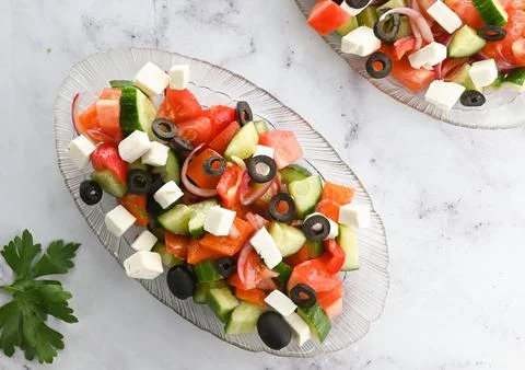 Fresh Greek salad in a bowl on a light background, top view. Stock Photos