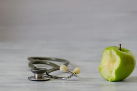 Fresh green apple with a bite isolated and stethoscope  on white  wooden back Stock Photos