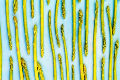 Fresh green asparagus pattern, top view. Isolated over blue. Food background  库存照片