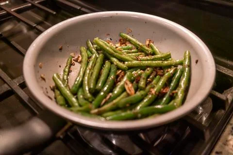 Fresh green beans and almonds frying in butter on gas stove Stock Photos