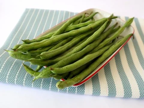 Fresh green beans on a rectangular plate with a blue cloth underneath Stock Photos