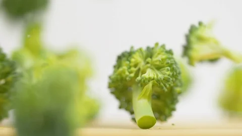 Fresh green broccoli falling down on wooden kitchen surface in slow motion. Vita Stock Footage 119847001