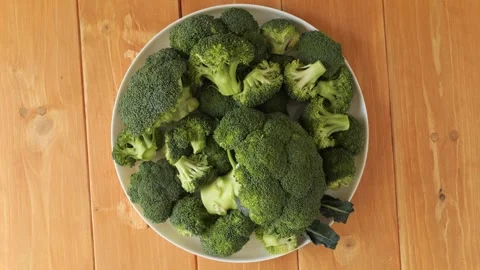 Fresh green broccoli florets rotating on a plate Stock Footage 342437043