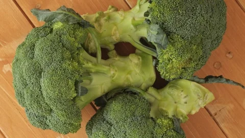 Fresh green broccoli florets rotating slowly on wooden table Stock Footage 344897481