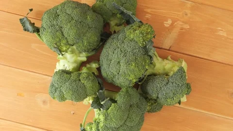 Fresh green broccoli florets slowly rotating on a wooden table Stock Footage 338312262