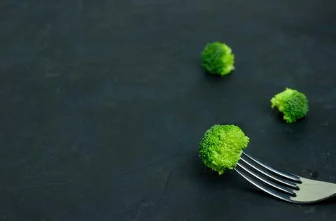 Fresh green broccoli on the fork. Pattern healthy eating on a dark background Stock Photos