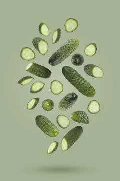 Fresh green bumpy cucumber whole, sliced fly or fall as swirl art composition Stock Photos