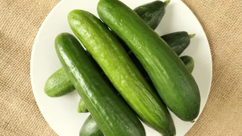 Fresh green cucumbers rotating on a plate Stock Footage 335559989