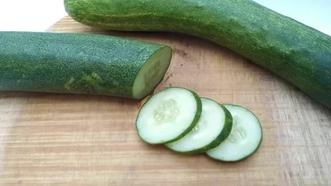 Fresh green cucumbers whole, half, and sliced on a round wooden cutting boa.. Stock Footage 340598206