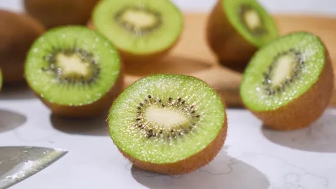 Fresh Green Kiwi Fruit Halves Sliced on Wooden Table in Bright Sunlight Stock Footage 340934744