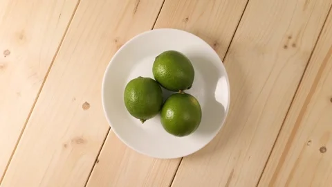 Fresh green limes rotating on a white plate Stock Footage 339366988