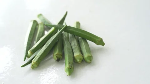 Fresh green okra pods placed on a clean white surface Stock Footage 337976330
