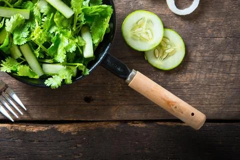 Fresh green salad with cucumber slices on rustic wooden table Stock Photos