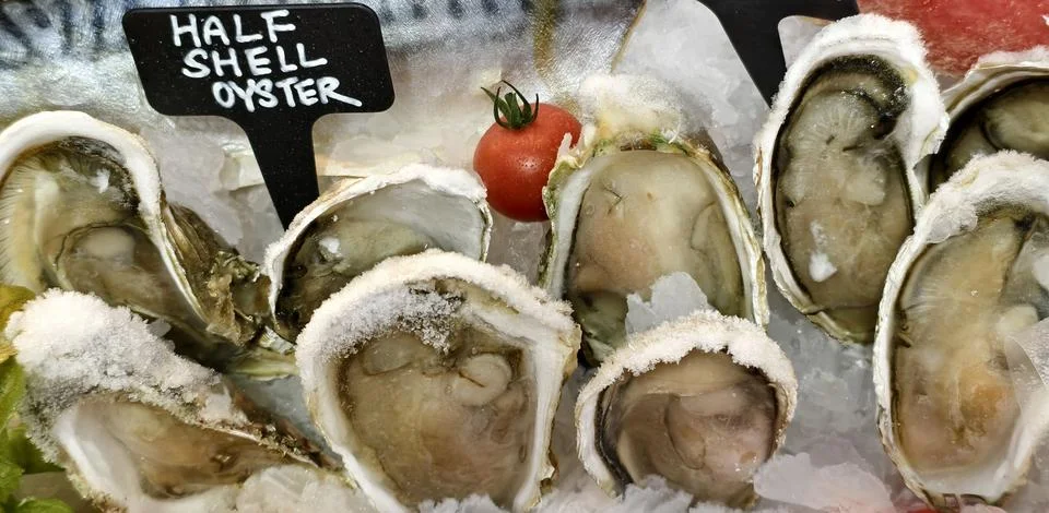 Fresh half‑shell oysters displayed on a bed of crushed ice Stock Photos