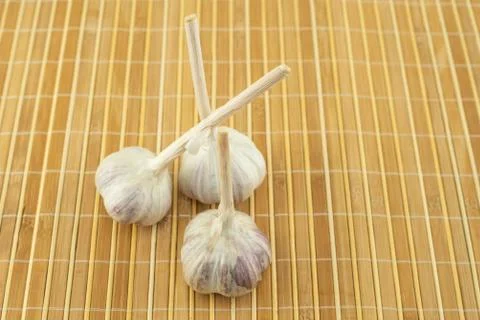 Fresh head of garlic three root vegetables stands on a wooden mat Stock Photos
